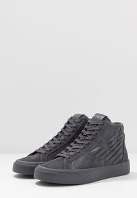 Höga sneakers i mörkgrå mocka med tonala snören. Har en strukturerad sidopanel och en gummisula. Rundad tådesign.