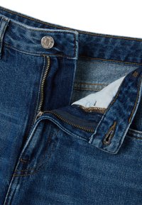 Dunkelblaue Jeans aus Denim mit einem Metallknopfverschluss und einem Reißverschluss. Die Innenverkleidung ist sichtbar und zeigt kontrastierende Nähte sowie die Textur des Stoffes.