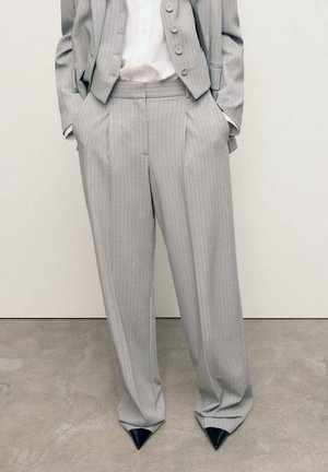 Pantaloni in tessuto grigio a righe con vestibilità comoda, dotati di tasche laterali e abbinati a décolleté nere a punta.