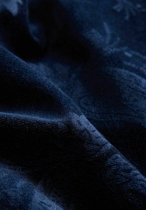 Dark blue textured fabric with subtle floral patterns and soft folds creating depth and shadow.
