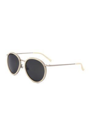 Occhiali da sole rotondi con lenti nere e sottili montature e stanghette beige chiaro, mostrati leggermente inclinati su uno sfondo bianco.