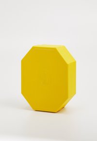 Gele achthoekige doos met een gestructureerd oppervlak en een reliëflogo. Solide vorm met scherpe randen en een gladde afwerking, ontworpen voor opslag.