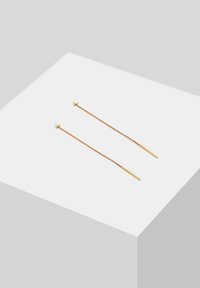 Guldtonade örhängen med pärl accenter; lång kedje-design med en smal, rak post och rundade ändar. Slät textur, minimalistisk stil.