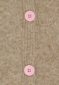 Beige uldstrikket cardigan med to lyserøde knapper, hver med to huller, placeret centralt på forsiden. Blød tekstur med subtile variationer.