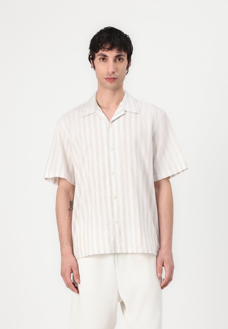 Κοντομάνικο, ανοιχτό μπεζ πουκάμισο με κάθετες λευκές ρίγες; διαθέτει ανοιχτό γιακά και χαλαρή εφαρμογή. Φτιαγμένο από ελαφρύ ύφασμα.