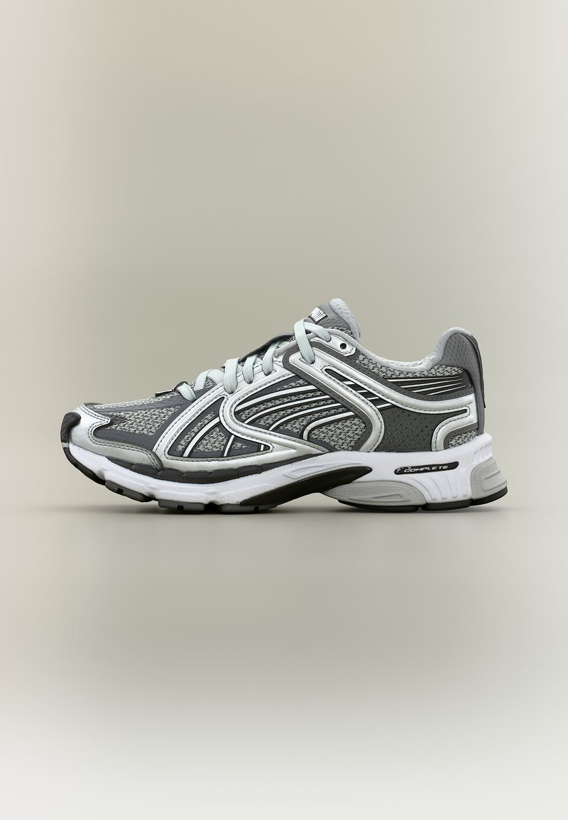 Sivá a biela športová teniska z sieťoviny s umelými prekrytiami, šnúrkami a polstrovanou podrážkou označenou "COMPLETE", zobrazená zboku.