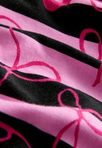 Svart tyg med alternerande rosa ränder och rosa bandmönster. Texturen verkar mjuk och något elastisk.