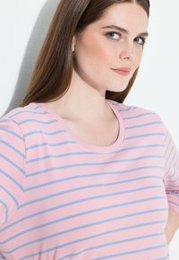 Rosa t-shirt med horisontella blå ränder, rundad halsringning, korta ärmar och mjuk textur. Tyget verkar lätt och avslappnat.