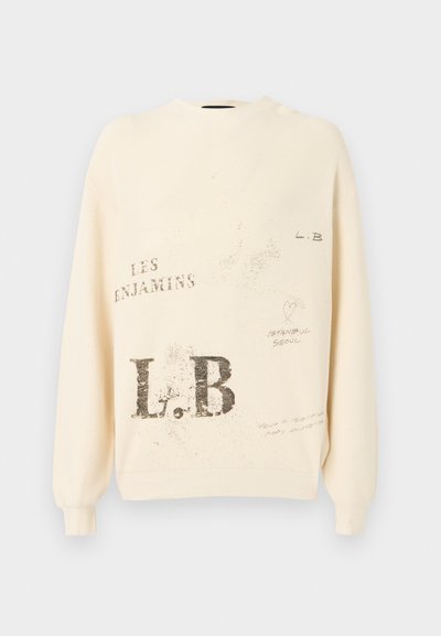 Sweat à couleur crème avec texture côtelée et manches longues. Comprend des textes et graphiques imprimés en gris, y compris "L.B" et "LES ENJAMINS."
