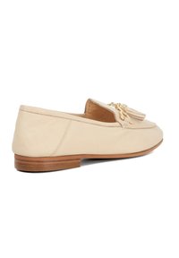 Beige leren loafers met een platte houten zool, voorzien van decoratieve franjes en gouden hardware accenten, een gladde textuur en een ronde neus. 