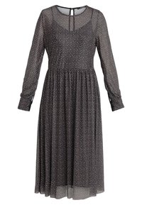 Robe noire fluide à manches longues, ornée de petits pois beige et rouille, avec un corps ajusté et une taille froncée.