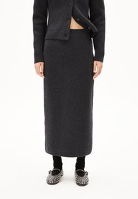 Długa wełniana spódnica w ciemnoszarym kolorze z dopasowanym pasem. Połączona z czarnymi legginsami i butami zdobionymi srebrnymi detalami. Miękka tekstura i gładki design.