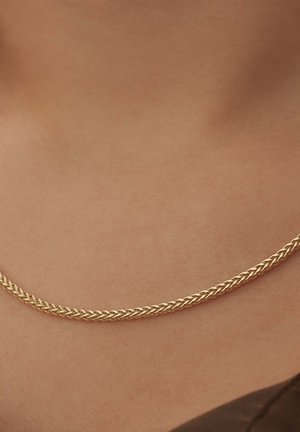 Collier en chaîne en or avec un design tressé, présentant une texture lisse et brillante qui repose élégamment sur la peau.