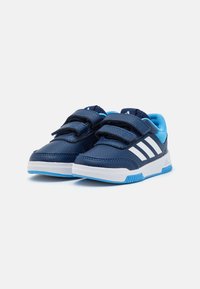 Scarpe da ginnastica blu navy con due cinturini in Velcro, design a tre strisce bianche e accenti azzurri. Materiale testurizzato e suola in gomma.