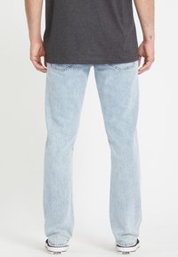 Lichtblauwe denim jeans met een rechte snit, vijf-pocket ontwerp en zichtbare stikseldetails. Gecombineerd met een donkergrijze shirt.