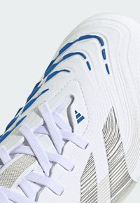 White athletic shoe featuring blue accents and textured stripes. Lace-up design with a mesh and synthetic upper for breathability.