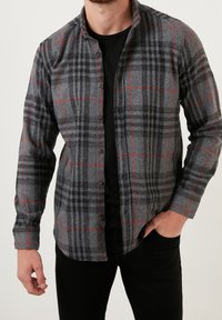 Camicia a quadri grigia con accenti rossi, realizzata in flanella, con un frontale a bottoni, maniche lunghe e vestibilità regolare.