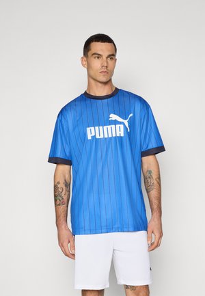 Blå atletisk trøje med lodrette striber, korte ærmer og rund halsudskæring. Har hvidt "PUMA" logo og emblem på brystet.