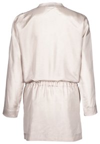 Light beige satin garment with long sleeves and a cinched waist. The back features a simple round neckline and smooth texture.