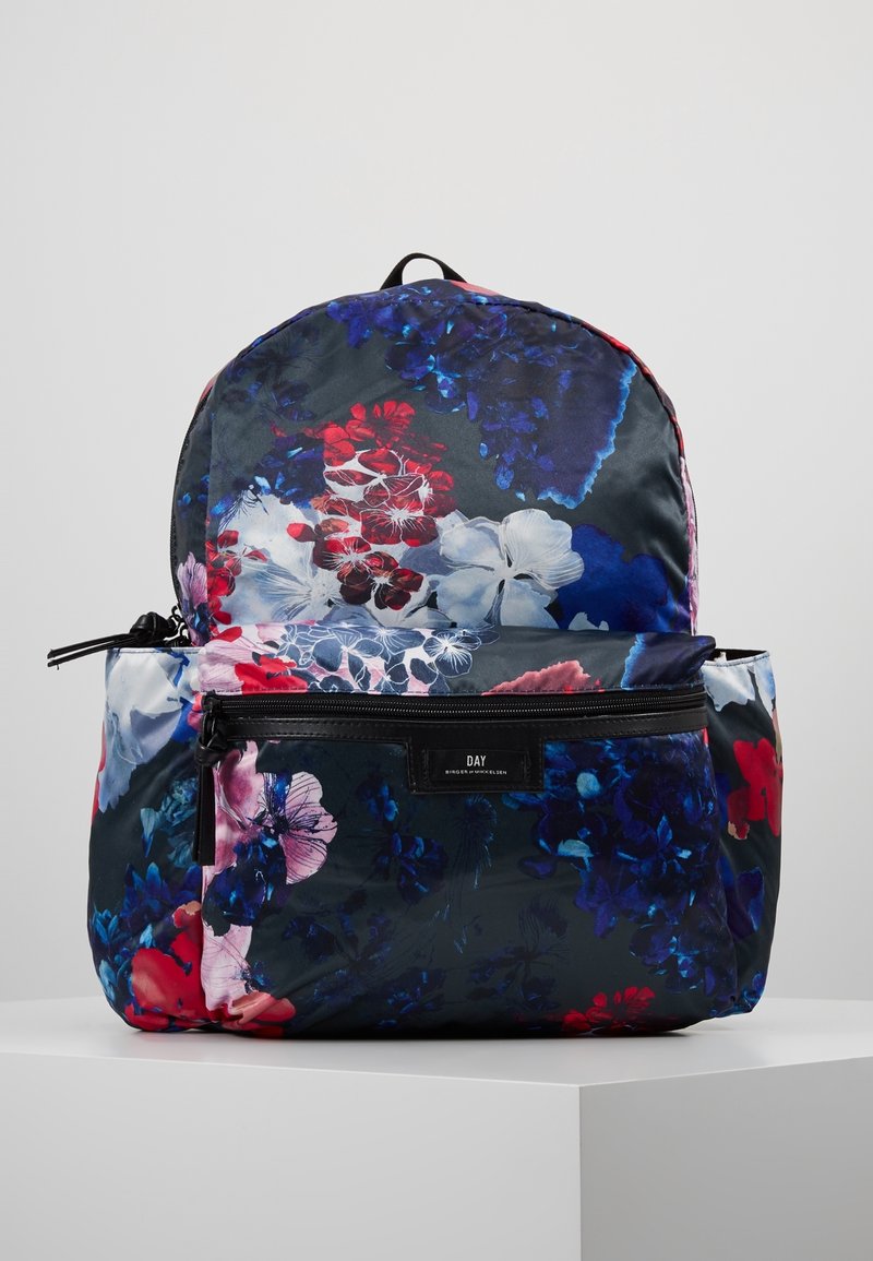 Reppu, jossa on vetoketjullinen etutasku, koristeltu monivärisellä kukkakuvioinnilla sinisen, punaisen, valkoisen ja vaaleanpunaisen sävyissä, valkoisella näyttöpinnalla.