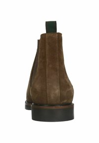 Stivaletti in suede marrone con punta rotonda, pannelli laterali elasticizzati e suola nera a contrasto. Predisposta a un anello verde sul retro.