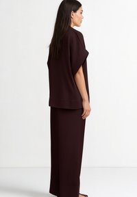 Completo bordeaux composto da una maglia ampia con ampie maniche e pantaloni a vita alta a gamba dritta in un materiale morbido.