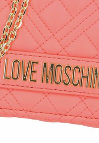 Borsa a tracolla in tessuto trapuntato corallo con catena in tonalità oro e logo "LOVE MOSCHINO" in caratteri grassetto su un pannello liscio. Superficie testurizzata e dettagli metallici.