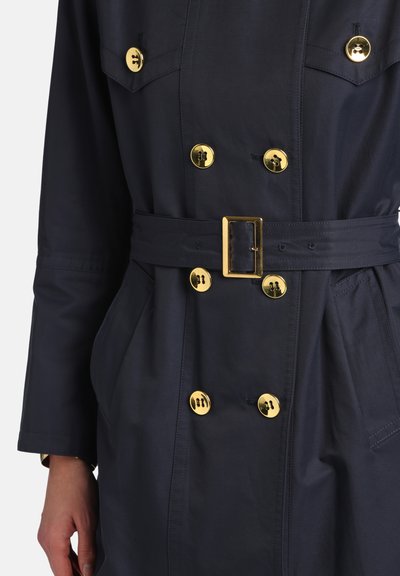 Palton de tip trench bleumarin cu nasturi aurii, talie cu curea și design cu două rânduri de nasturi; prevăzut cu buzunare și textură netedă.