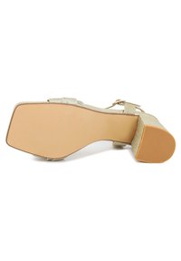 Sandalo con tacco a triangolo in glitter oro, con punta quadrata, cinturino alla caviglia regolabile e suola in gomma testurizzata. Tacco basso per stabilità.