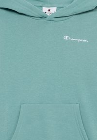 Felpa verde menta realizzata in morbido tessuto con tasca frontale, caratterizzata da un piccolo logo "Champion" ricamato nella zona del petto.