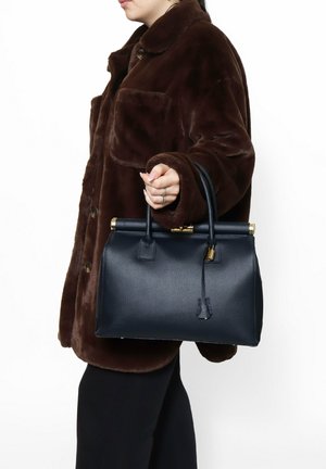 Borsa a tracolla in pelle blu navy con forma strutturata, manici superiori e hardware in tonalità oro. Superficie texturizzata con un dettaglio a forma di portachiavi removibile.
