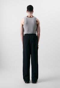 Gray tank top and black loose-fitting pants with an elastic waistband and side pockets, viewed from the back against a light background.