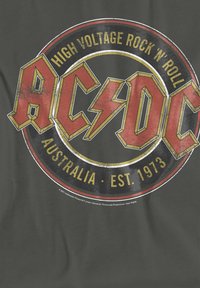 Black cotton T-shirt featuring AC/DC logo in red and yellow, centered on a circular graphic with "High Voltage Rock 'n' Roll" text.
