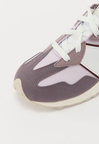 Lilla og lys rosa sneaker med overdel i semsket skinn og mesh, hvite detaljer, tykk såle og teksturerte mønstre på sidene.