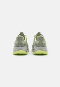 Des chaussures de sport grises et vertes, avec une tige texturée, une languette de traction, des accents réfléchissants et une semelle en caoutchouc verte dotée de motifs de traction.