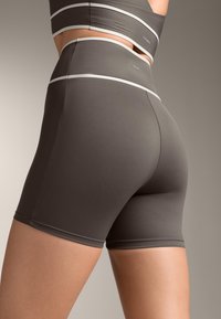 Visoko tienti kratke hlače, ki se lepo prilegajo, v gladkem temno sivi tkanini z kontrastnimi belimi črtami ob pasu.