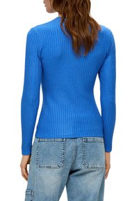 Gestreifte blaue Langarmoberteil mit schmaler Passform, kombiniert mit hellblauen hochgeschnittenen Jeans. Der Stoff wirkt weich und dehnbar.