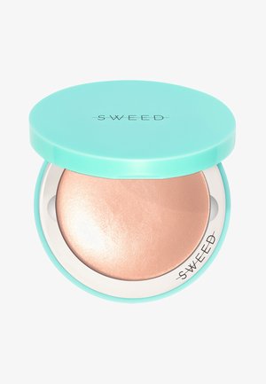Round compact with a turquoise lid, featuring a reflective, rose gold powder surface inside. Label reads "SWEED." Smooth, shiny texture.