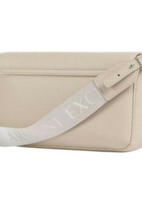 Borsa color beige chiaro realizzata in pelle texturizzata, dotata di una singola tracolla regolabile con la scritta "Armani Exchange" stampata in bianco. Chiusura con zip sulla parte superiore.