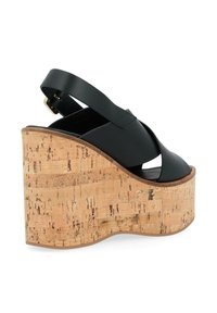 Sandali con zeppa in pelle nera, caratterizzati da una punta aperta, design con cinturino incrociato e suola piattaforma con motivo in sughero. Include cinturino alla caviglia regolabile.