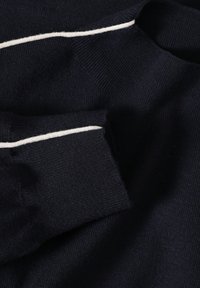 Marineblauer Strickpullover mit einem kontrastierenden weißen Streifen entlang des Kragens. Der Stoff wirkt weich mit einer strukturierten Oberfläche.