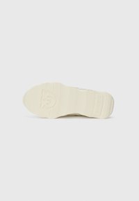 Suola di una sneaker, in gomma testurizzata color bianco sporco con un logo e motivi scanalati, dotata di una punta arrotondata e una struttura di supporto.
