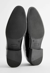 Schwarze Lackledersohlen mit einer strukturierten Gummigrifffläche, ausgestattet mit einem eckigen Absatzdesign und der Größenangabe 42.