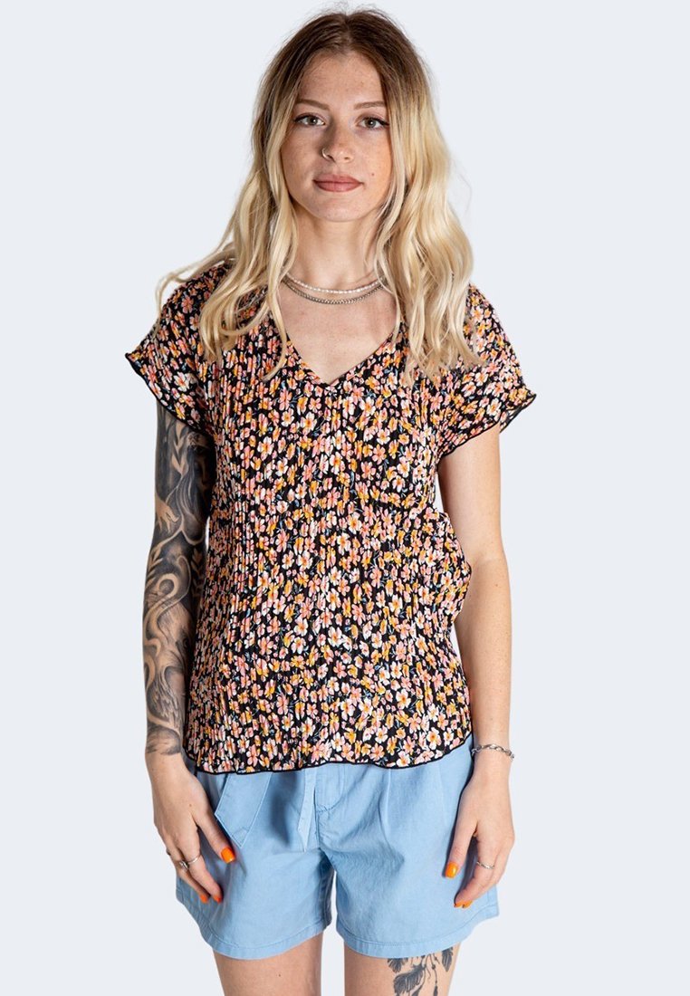 Haut à motifs floraux avec une base noire, doté de manches courtes et d'un décolleté en V. Fabriqué en tissu léger, associé à un short bleu clair.