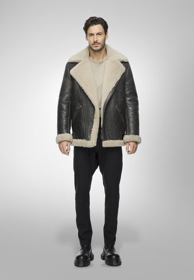 Giacca in shearling nera con colletto e polsini in pelliccia sintetica beige, caratterizzata da un design doppiopetto e tasche con zip.