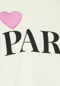 Tela blanca con "PAR" en letras negras en negrita y un corazón bordado rosa encima del texto. La textura es suave y lisa.