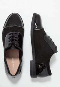 Chaussures oxford en cuir verni noir et suède, avec un bout rond, un laçage à l'avant, des clous décoratifs en argent, et une semelle en caoutchouc plate et basse.