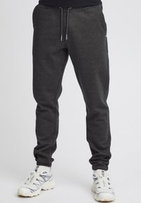 Donkergrijze sweatpants van zacht materiaal, met een elastische tailleband met trekkoord, taps toelopende benen en zijzakken.