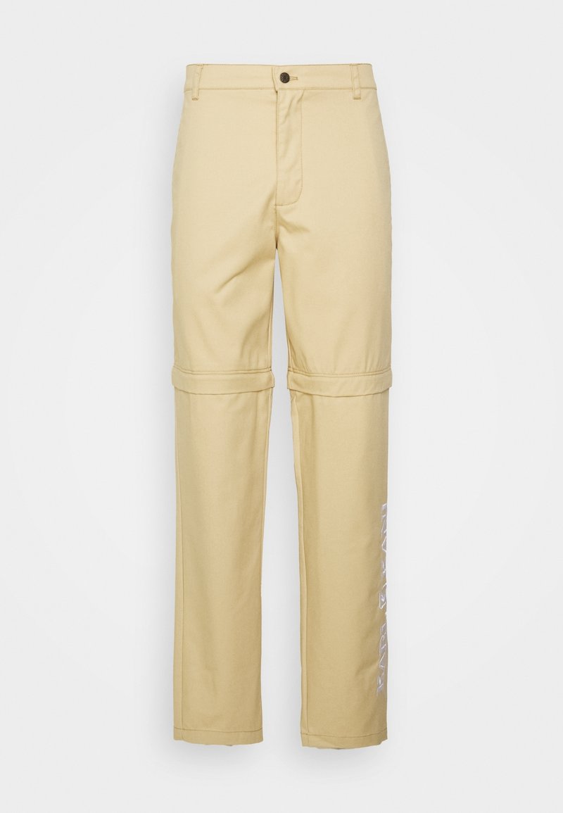 Pantalons droits beige avec une fermeture à bouton, dotés d'une couture pour se transformer en version roulée et d'un texte imprimé le long de la jambe gauche.