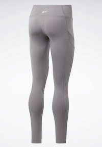 Šedé sportovní legíny vyrobené z elastického materiálu, s vysokým pasem, bočními kapsami a žebrovanými akcenty po stranách.